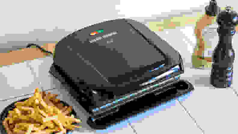 A black George Foreman 4-Serving Removable Plate Grill viewed from a front right angle.