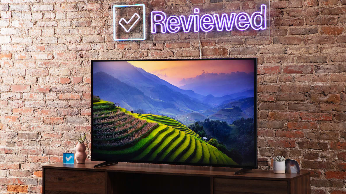 The Sony X90K LED TV displaying a nature scene with green, step hills and a blue and orange sunset.