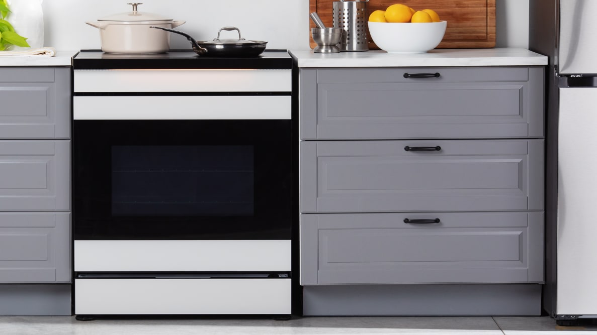 The Samsung Bespoke NSI6DB990012AA Induction Range between grey cabinets in a kitchen.