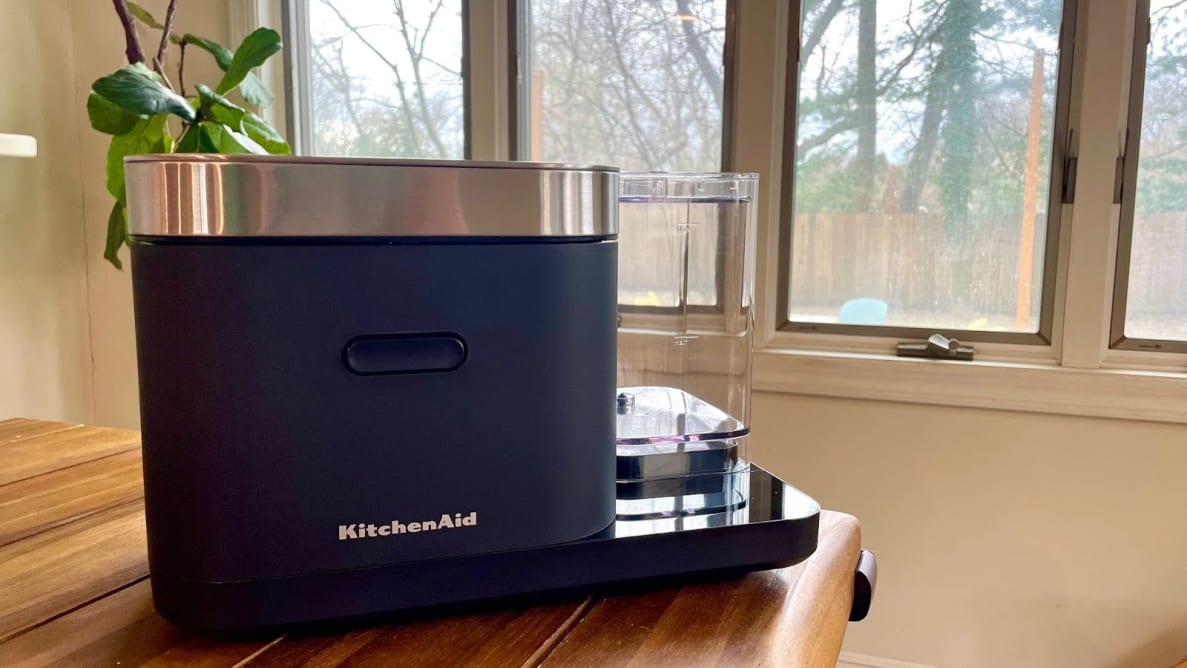 Navy blue KitchenAid Grain and Rice Cooker sitting on wooden countertop in front windows.