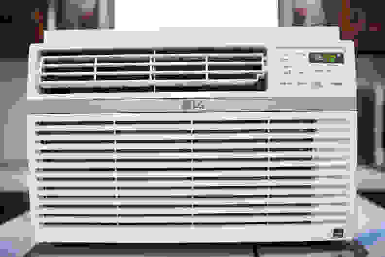 A white LG LW8016ER Window AC unit is placed on a table in front of a window, in contention for a top slot among the best window air conditioners..