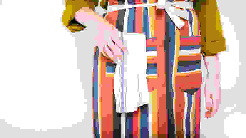 A close-up image of a person wearing an apron their hand in the pocket.