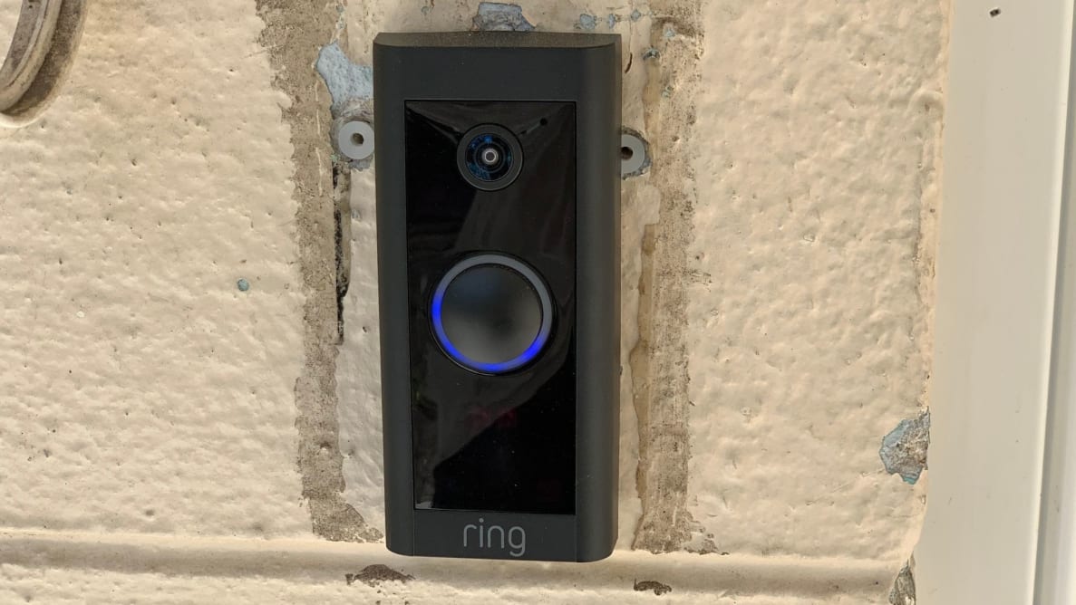 The Ring Video Doorbell Wired hangs on the front of a home.