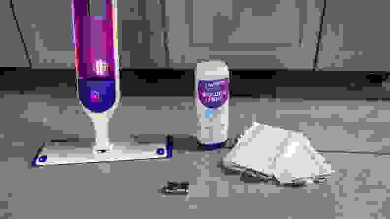 A Swiffer Powermop system is positioned next to a bottle of cleaner, mop pads, and parts during testing for the best mop.