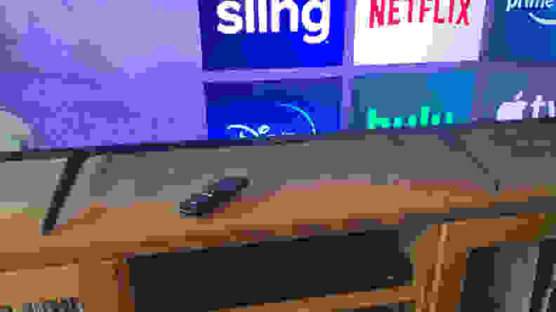 A closeup of the TCL 5-Series feet with a Roku remote sitting on a wooden table.