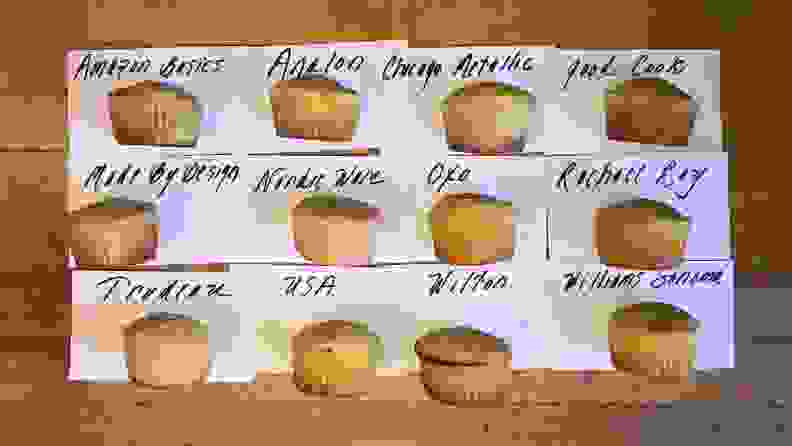 Twelve muffins lined up in three rows, each one baked in a different pan to show how we tested