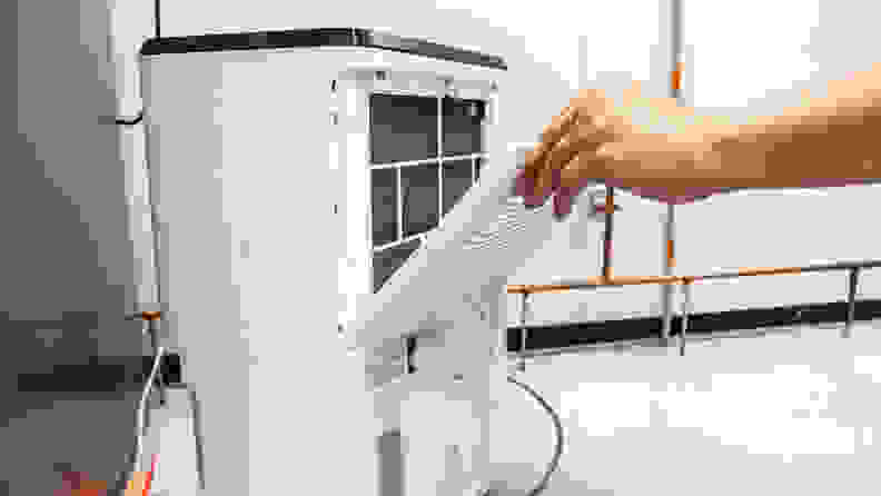 A person slides a filter into a dehumidifier during lab testing of the best dehumidifiers.