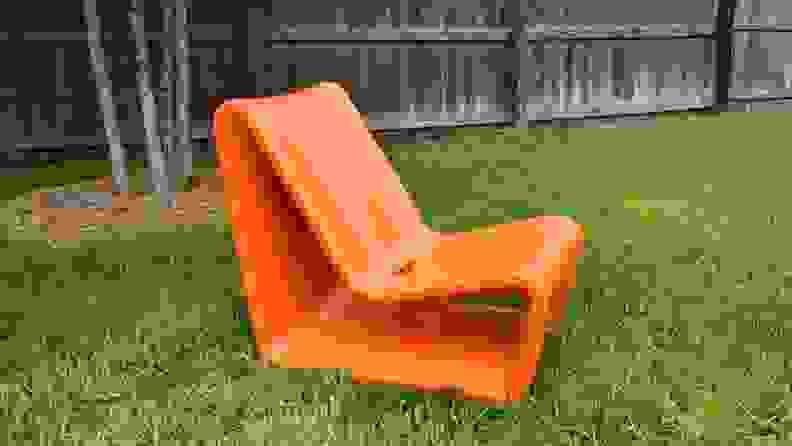 An orange modern Loop Chair from Tupelo Goods sitting in a green yard