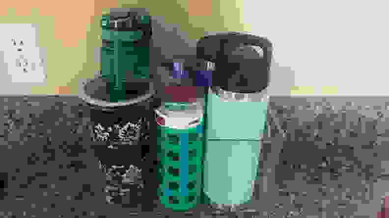 A clear plastic bin on a countertop with six water bottles of various sizes.