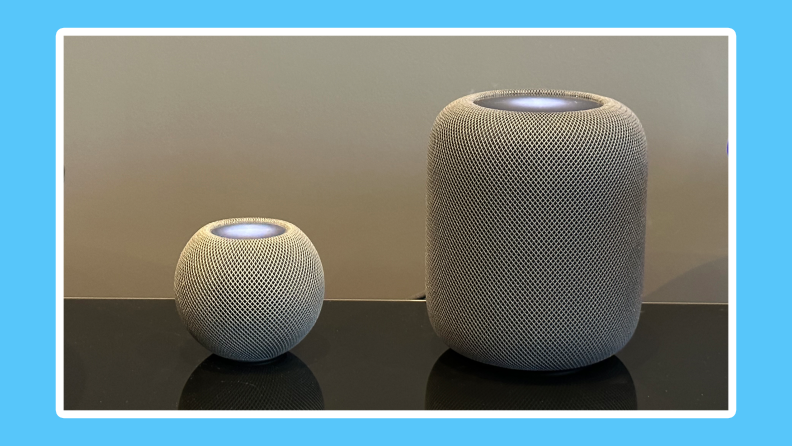 Apple HomePod Mini and HomePod side by side on black surface.