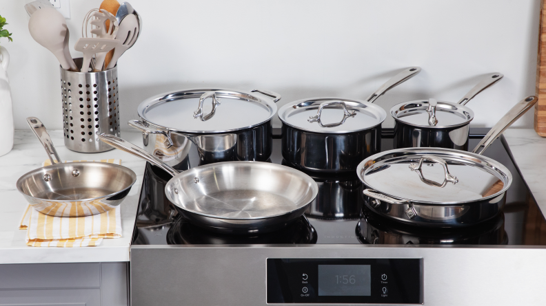 All Clad stainless steel set laid out on a range cooktop