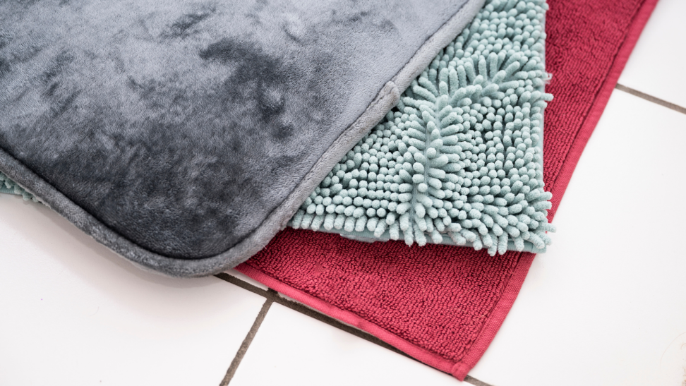 Three bath mats on a bathroom floor.