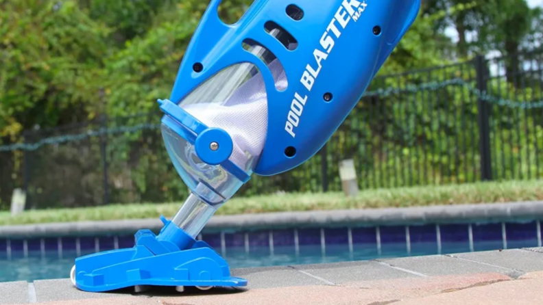 The Water Tech Pool Blaster Max manual pool vacuum in front of an in-ground pool.