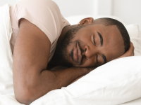 Black man sleeping peacefully with pillow