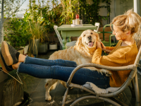 A young adult and their dog enjoys a moment together outside on an apartment balcony.