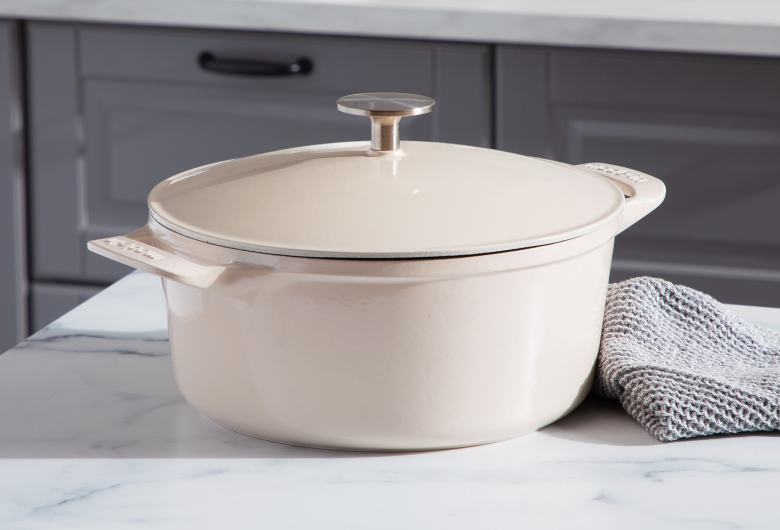 A beige Dutch oven sits on a kitchen counter.