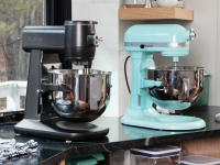 Black GE Profile and aqua KitchenAid stand mixer sit on a kitchen counter in front of a window.