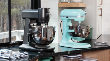 Black GE Profile and aqua KitchenAid stand mixer sit on a kitchen counter in front of a window.