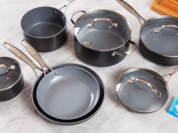 Several pieces of cookware on a white marble countertop, beside a Reviewed checkmark logo