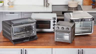 Four countertop ovens arranged on a wooden countertop