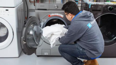 A person loading towels into a washing machine.