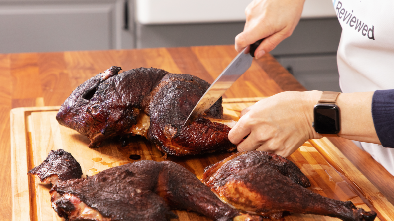 A person carving a smoked turkey.