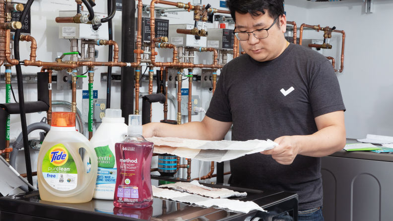 A person holding a towel next to a variety of eco-friendly laundry detergents