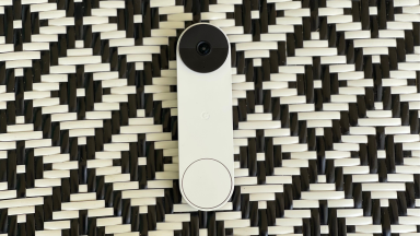 A white video doorbell sits on a black-and-white, diamond-patterned surface