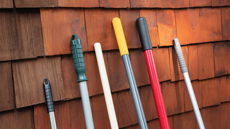 Rakes lean against a wall of a house.