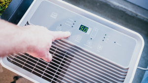 A Hisense DH7021K1W, one of the best dehumidifiers, is shown from the top, with a hand controlling it.